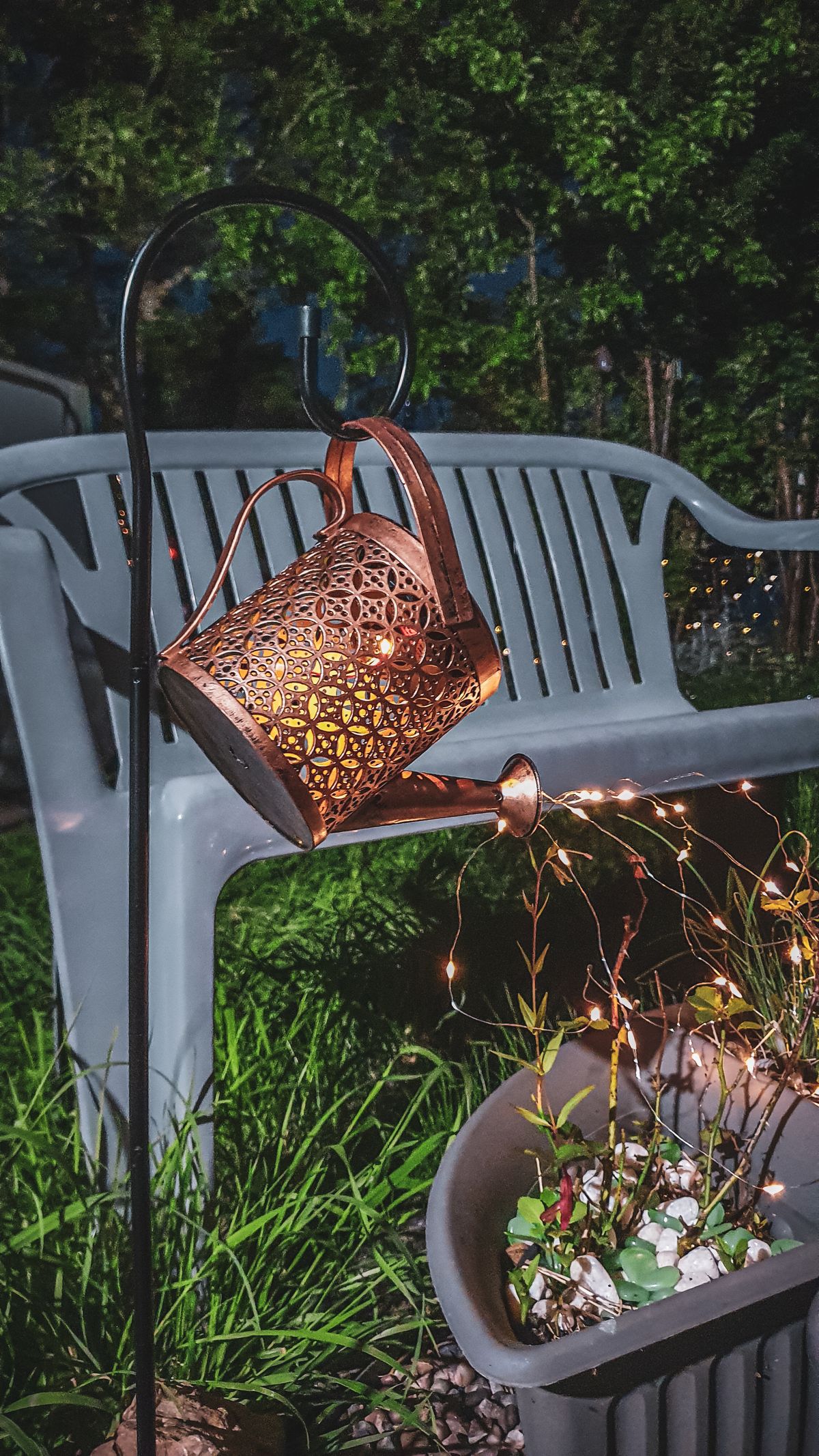 A decorative watering can with string lights creating a cozy outdoor ambiance. Stock Photo.