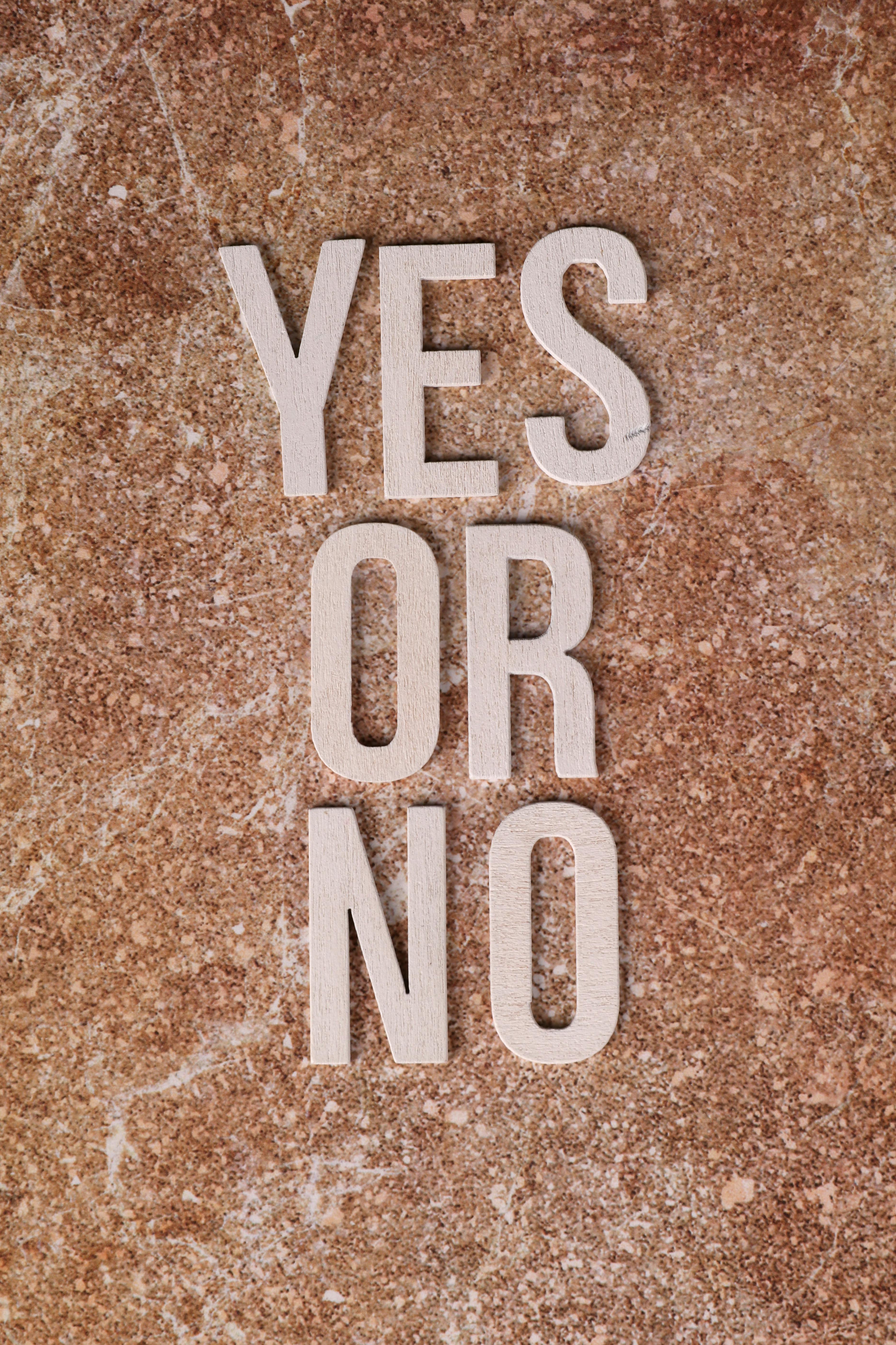 Text 'YES OR NO' on textured stone background, symbolizing decision making.