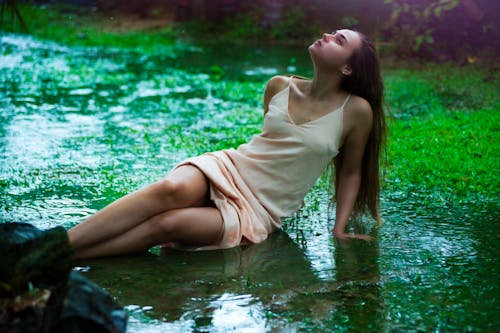 濡れた芝生のフィールドに横たわっている女性