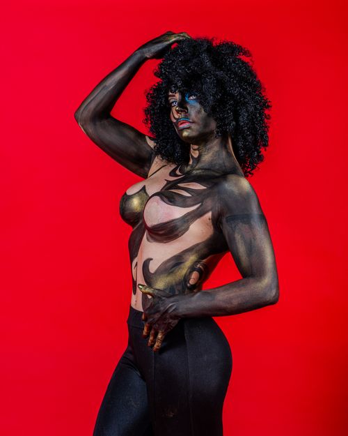 Free Expressive bodypaint portrait of a strong woman against a vivid red background. Stock Photo