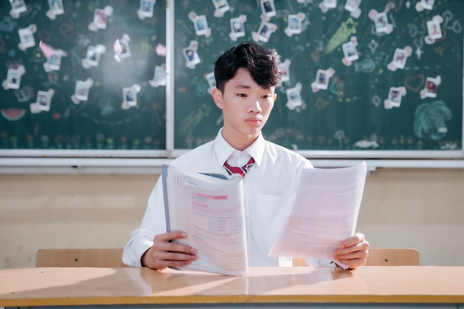 教室の机で集中して論文を読んでいる生徒。
