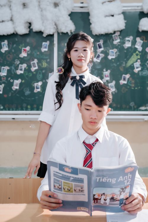 Free Two high school students studying with a textbook in a classroom setting. Stock Photo