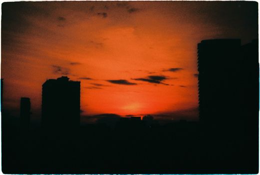 Silhouette of Singapore skyline against a vibrant sunset sky, creating a dramatic cityscape view.