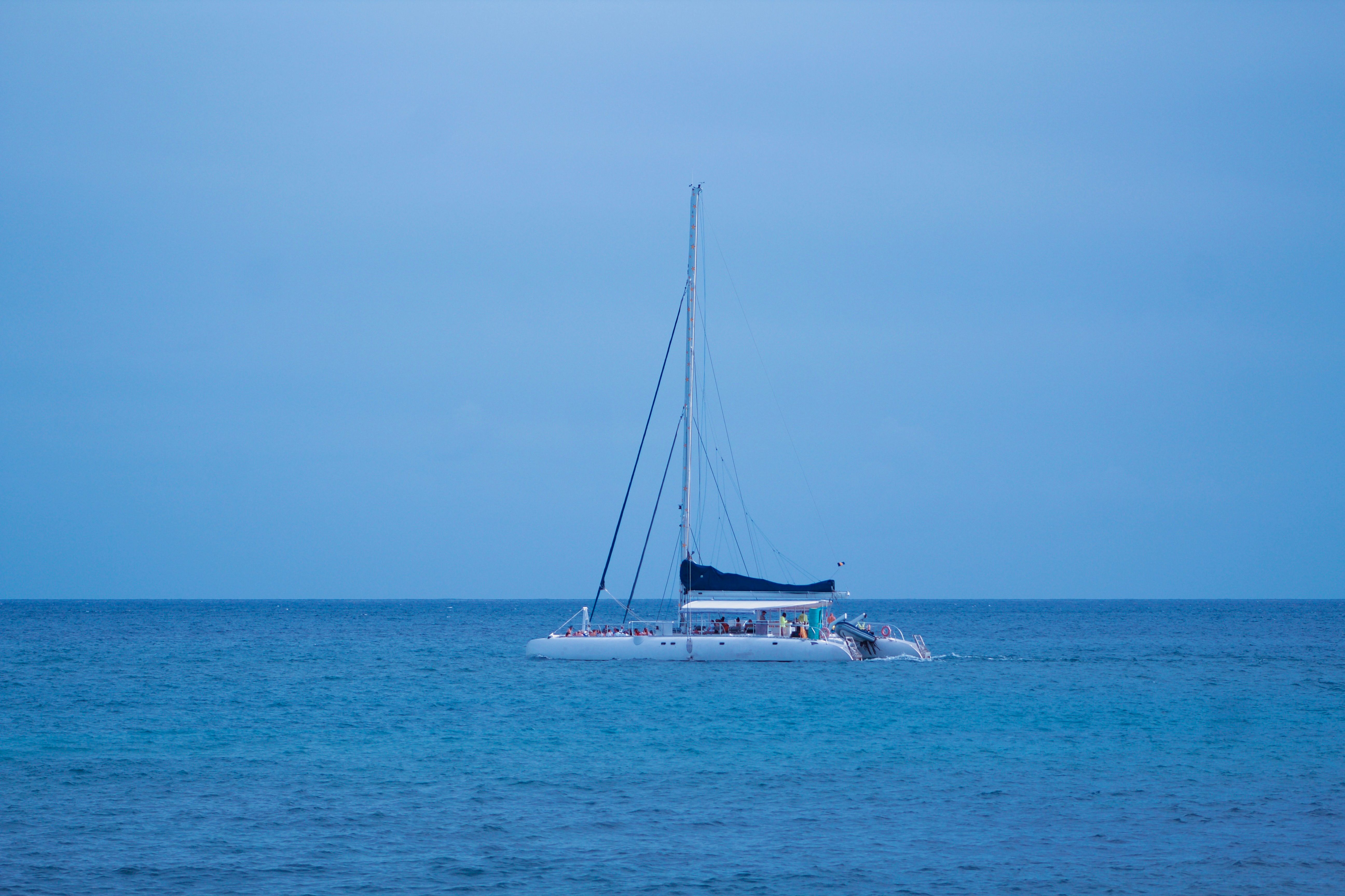 Best Luxury Diamond Head Sunset Sail Review: Hawaii's Most Romantic Evening on the Water Review 2026 - A sailboat cruises on the calm blue ocean under an overcast sky.