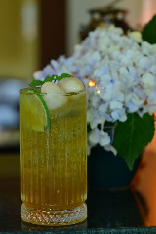 Free Chilled iced tea in a crystal glass with lychee and mint garnish, next to hydrangeas. Stock Photo