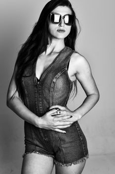 Chic black and white portrait of a woman in denim and sunglasses.