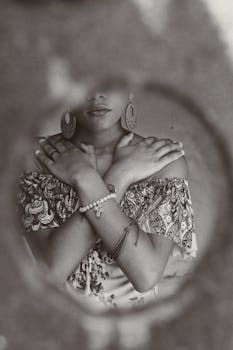 一位女性身着柔和图案连衣裙，双臂交叉，佩戴优雅珠宝的单色肖像