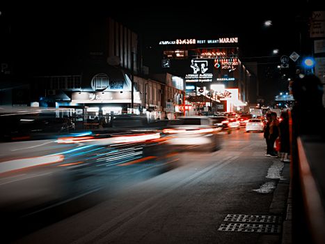 Dynamic night city scene with motion blur cars and visible neon signs.