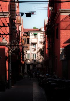 Sunlit alleyway with classic brick buildings in Shanghai, China.