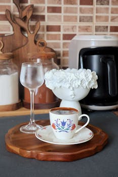 An elegant coffee setup with floral decor and ceramic mug on a wooden tray in a modern kitchen setting.