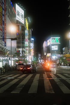 Busy nighttime street in Shinjuku, Tokyo with neon lights and bustling traffic.