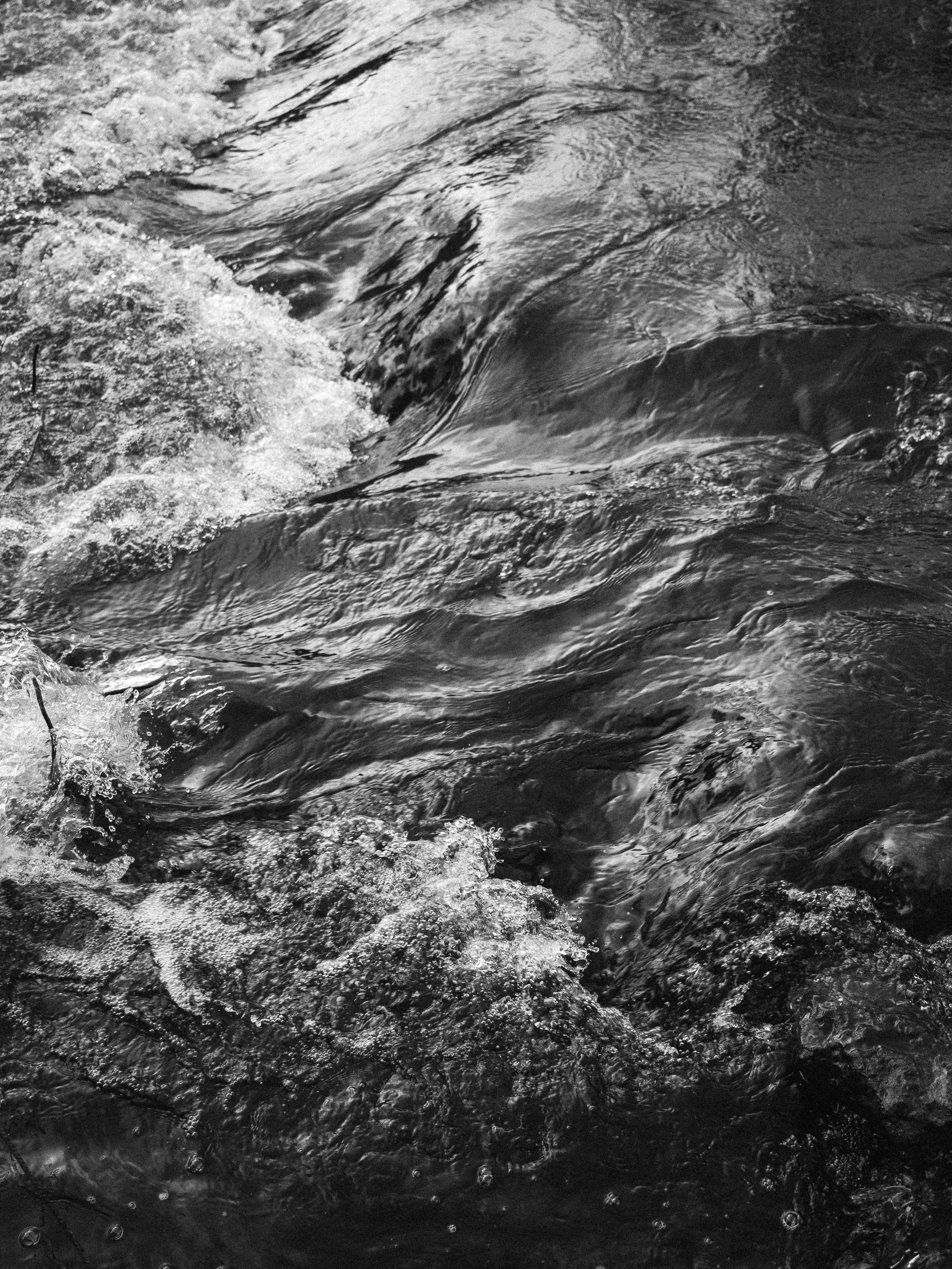 Black and white photo capturing the dynamic movement of river rapids, highlighting water textures.