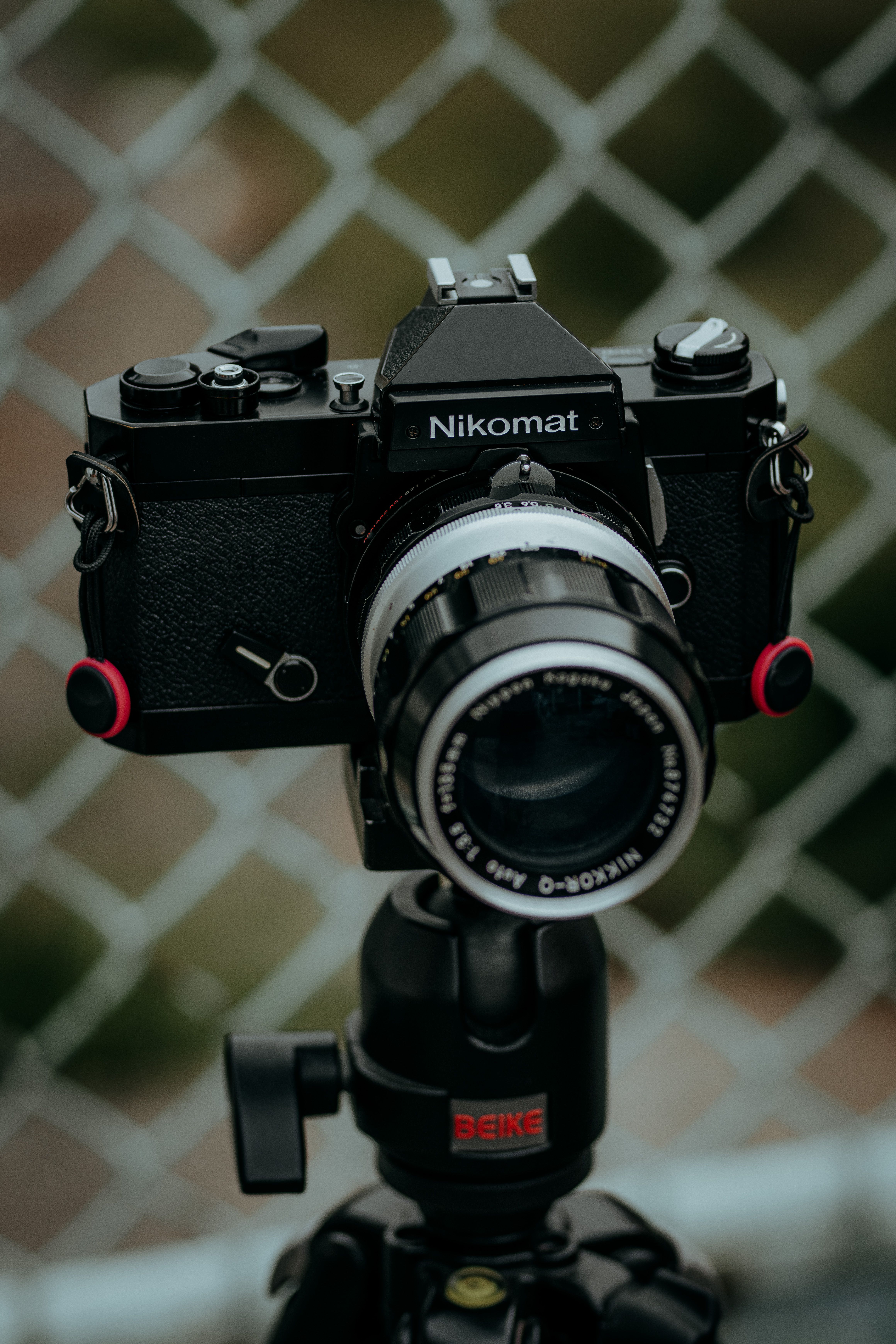 Close-up of a vintage Nikomat camera mounted on a tripod outdoors, perfect for photography enthusiasts.