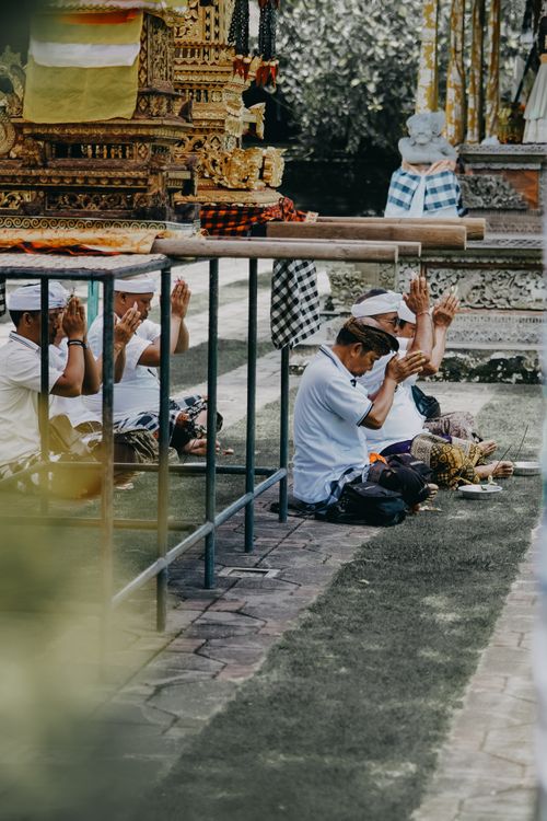 Free Group of Balinese men in traditional attire praying at a temple, showcasing a cultural spiritual ritual. Stock Photo