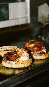 Delicious octopus sliders prepared with care on a grill, topped with creamy sauce and spices.