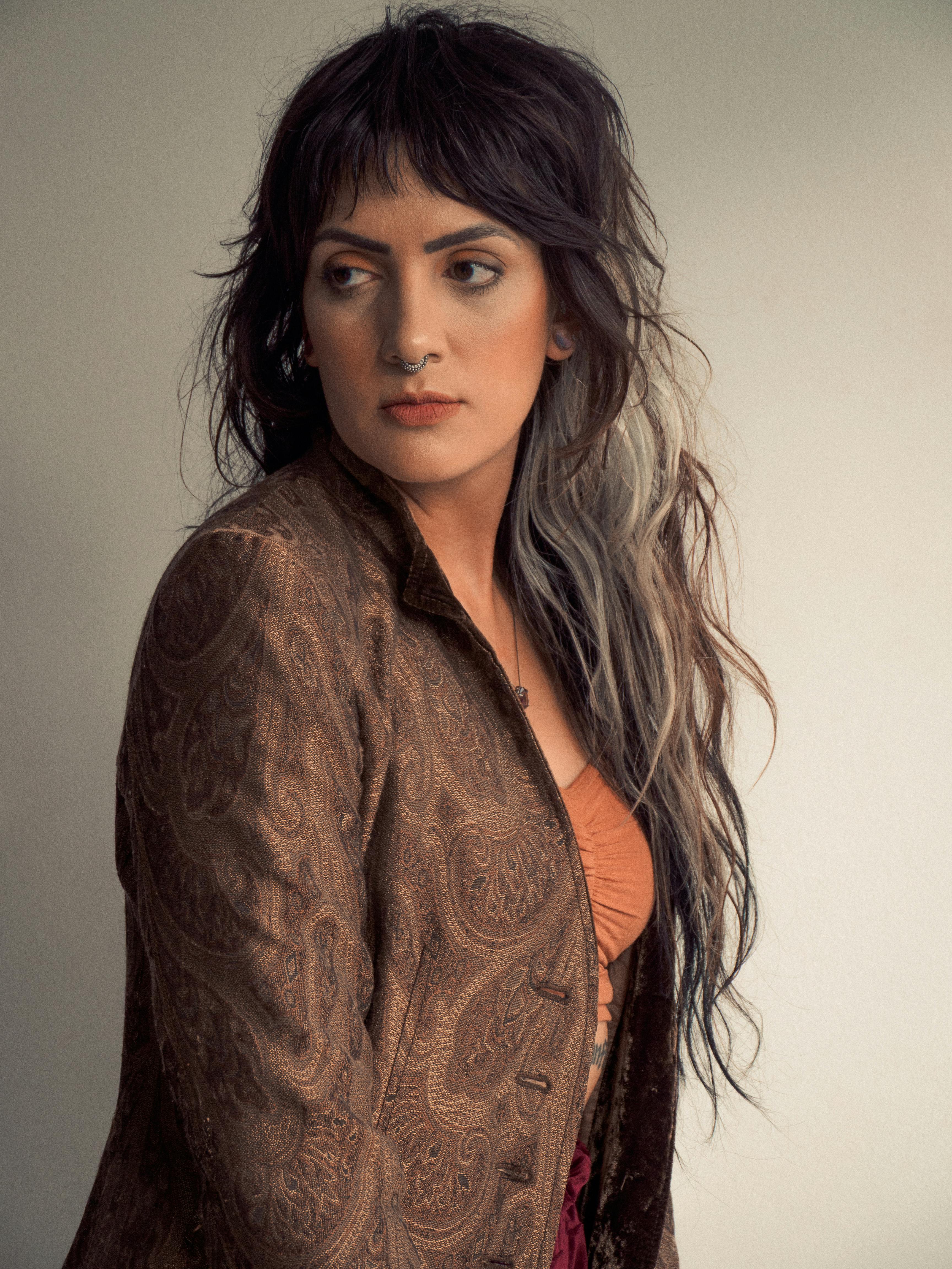 Portrait of a woman in a vintage paisley jacket with long hair, exuding bohemian style.