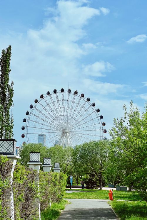 Free A sunny day view of a giant Ferris wheel in Astana surrounded by greenery. Stock Photo