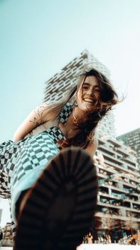 A young woman playfully kicks towards the camera against the Utrecht skyline, capturing a lively moment.