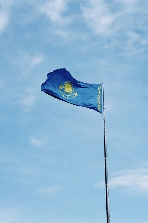 Free National flag of Kazakhstan waving against a clear blue sky in Astana. Stock Photo