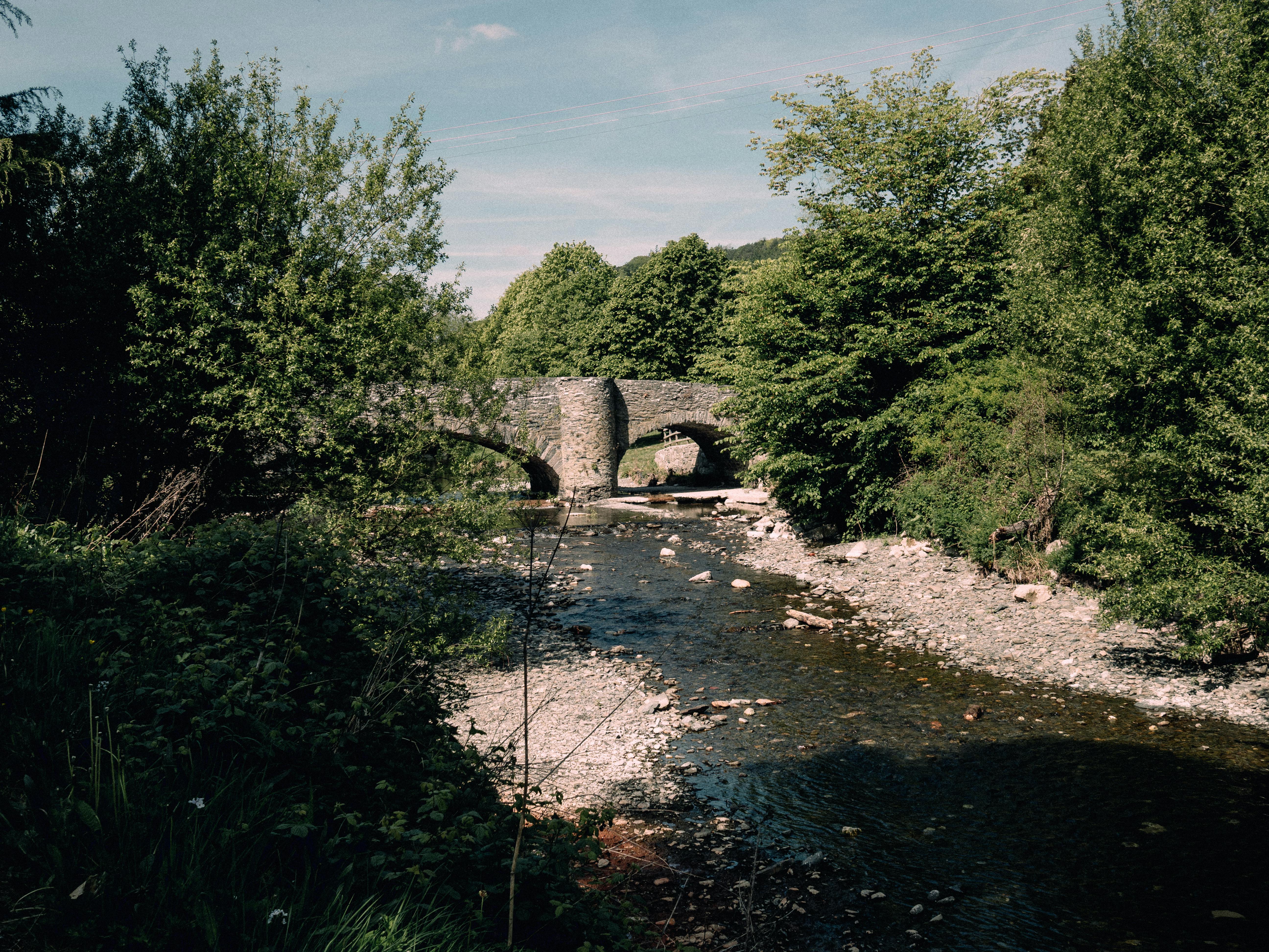 Serene view of a stone bridge spanning a tranquil river in Llanfair Talhaiarn, Wales.