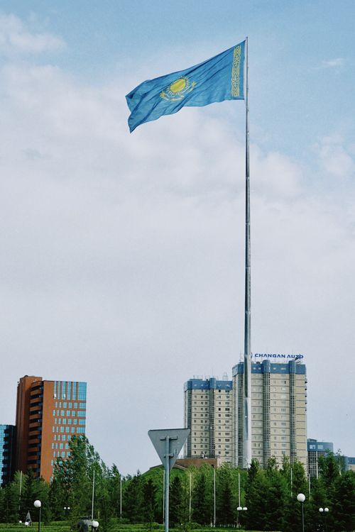 Free Kazakhstan flag waving over Astana skyline, showcasing national pride. Stock Photo