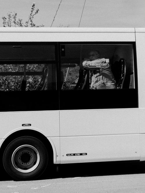 Free Monochrome image of a senior man looking out from a bus window, conveying travel. Stock Photo