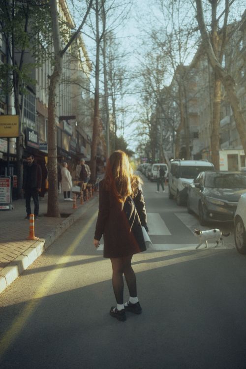 Free A young woman walks down an urban street in the morning light, capturing a serene city vibe. Stock Photo