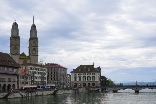 Free Beautiful cityscape of Zurich featuring Grossmünster along the Limmat River under a cloudy sky. Stock Photo