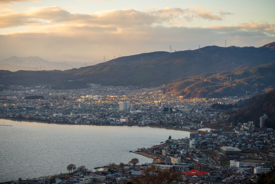A stunning aerial view of a city nestled by a lake surrounded by mountains at dawn.