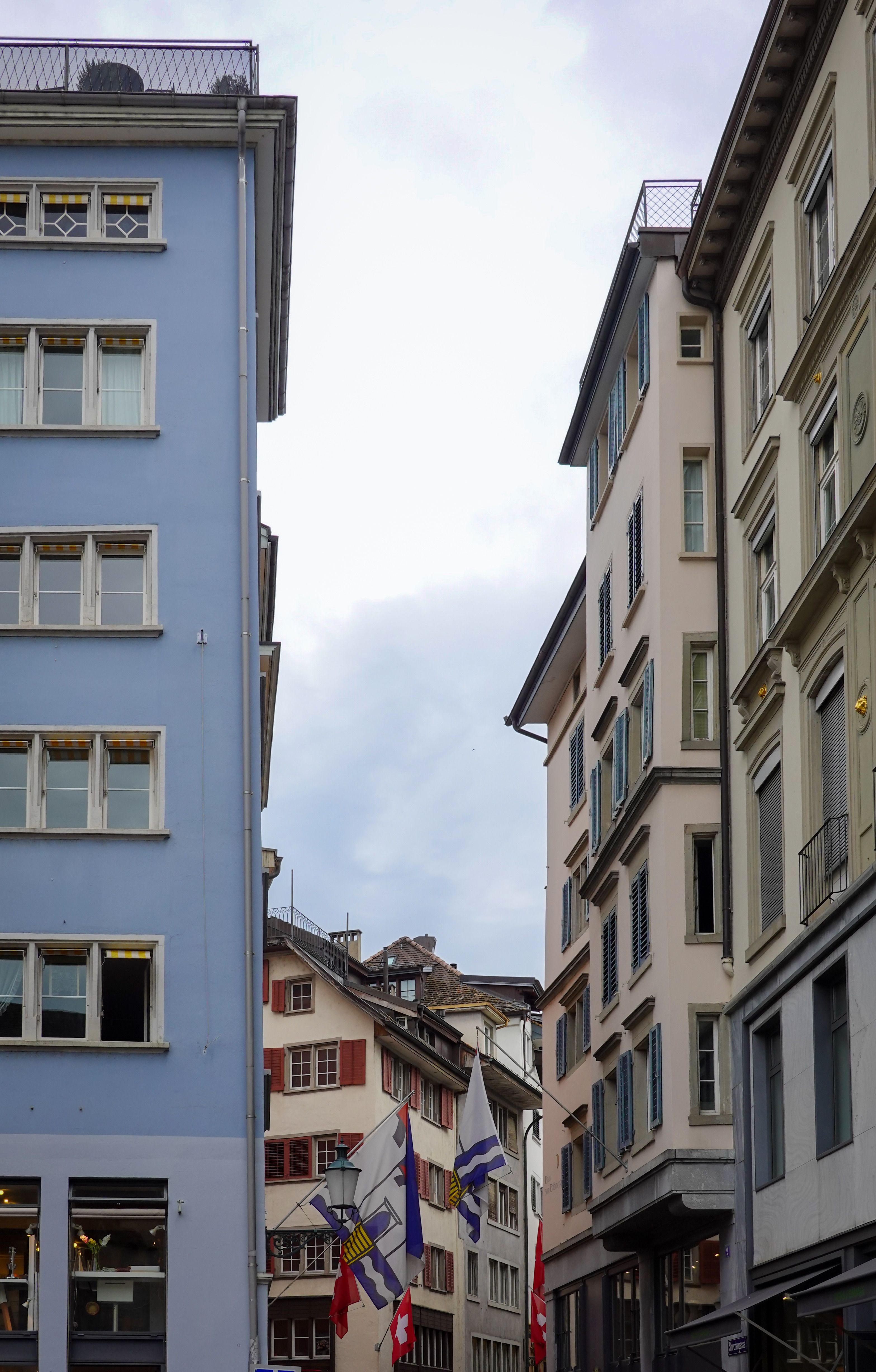 Discover the quaint charm of Zurich's historic architecture with flags waving in the street.