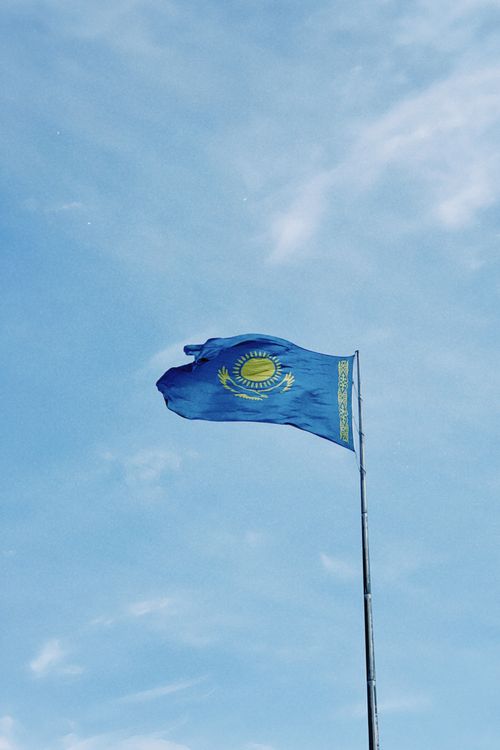 Free National flag of Kazakhstan waving on a pole against a clear blue sky in Astana. Stock Photo