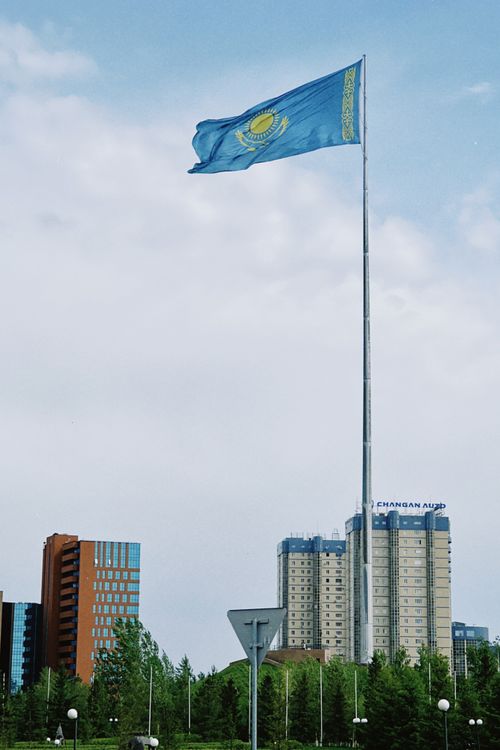 Free A majestic Kazakhstan flag waving proudly over modern buildings in Astana's cityscape. Stock Photo