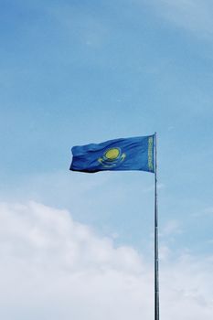 Kazakhstan flag waving on flagpole against a clear blue sky in Astana. Captures national pride.