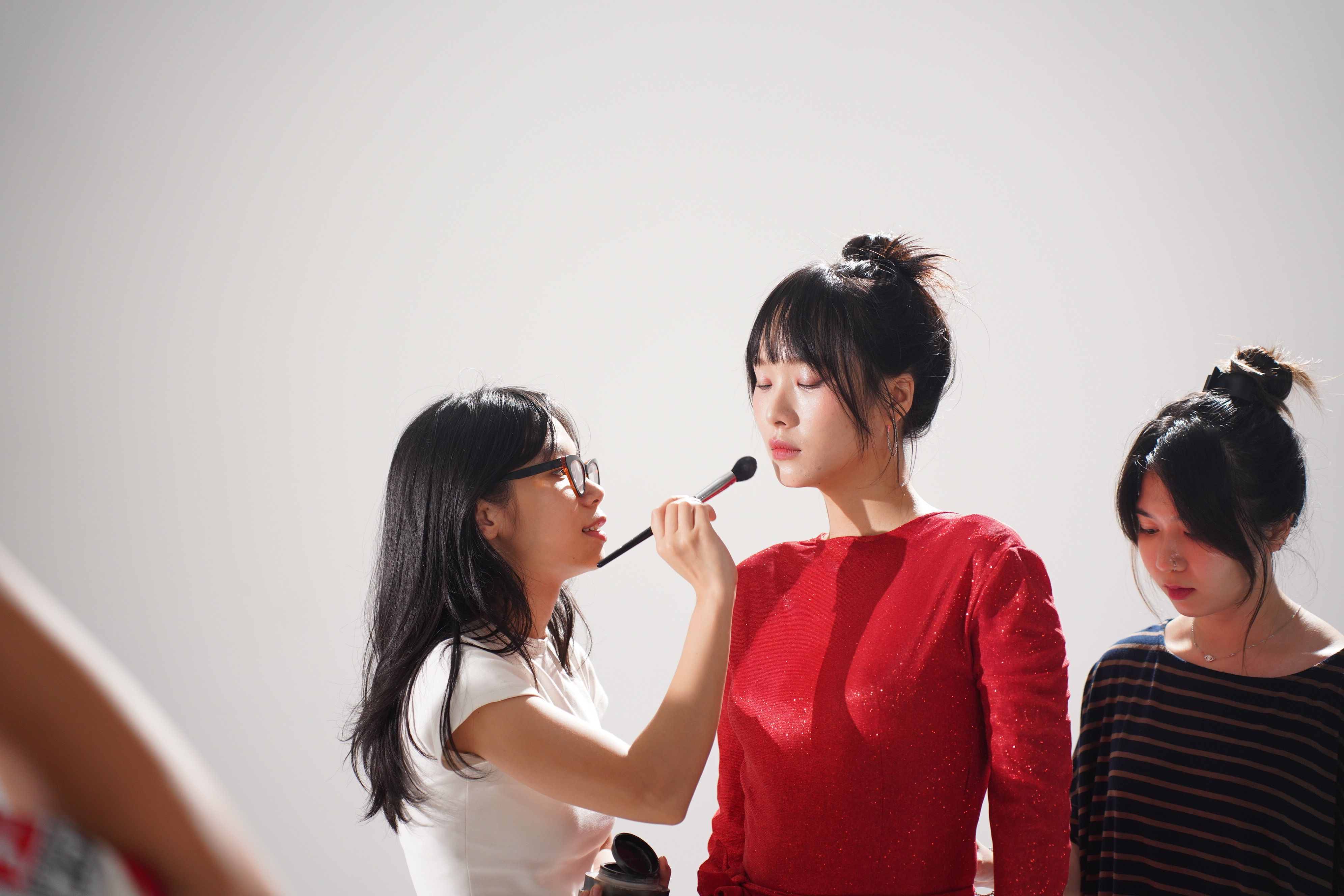 gratis Een ervaren visagiste brengt een delicate make-up aan op een model in een lichte studio-omgeving. Stockfoto