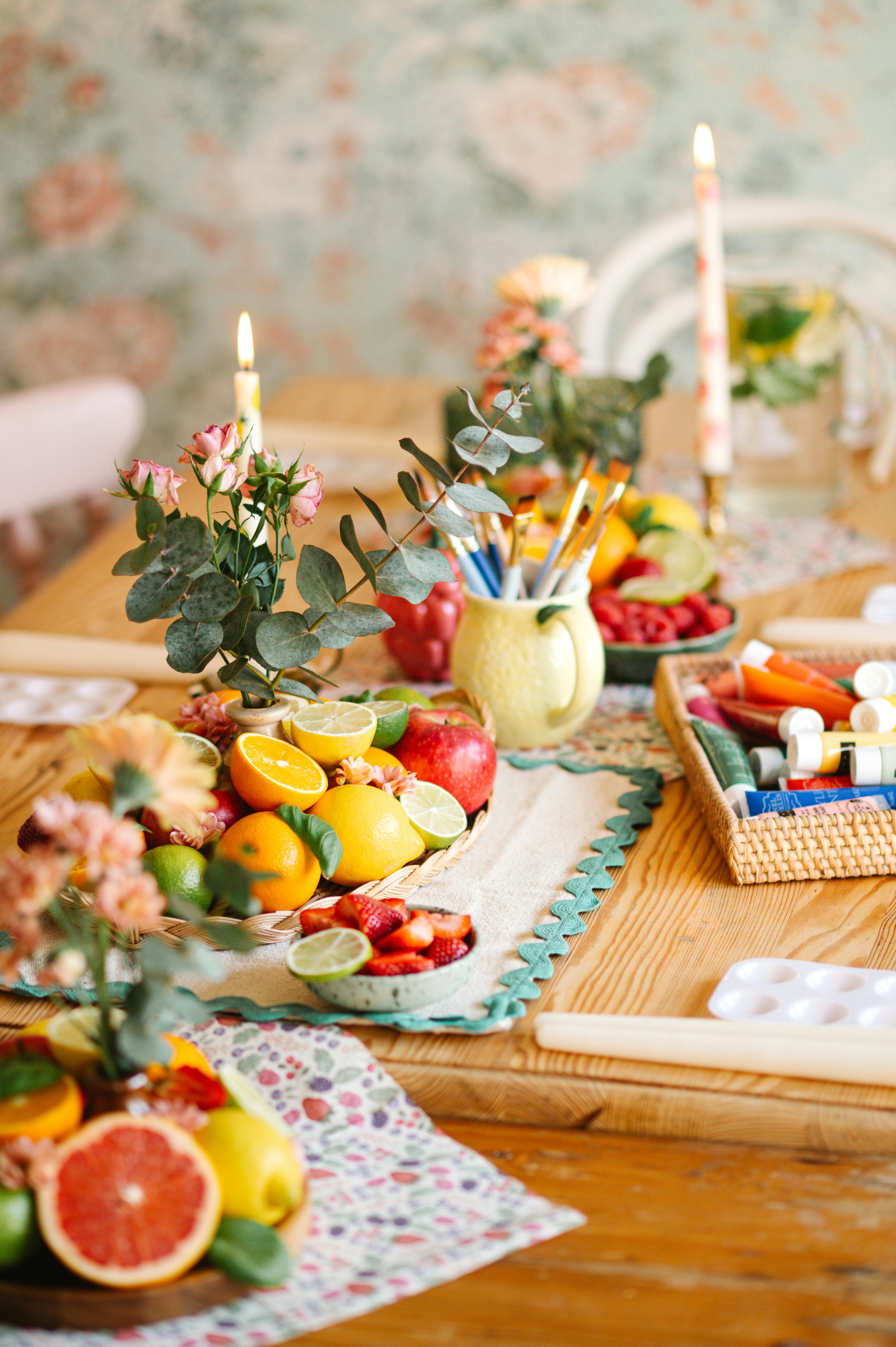Vibrant fruit and floral arrangement set on a rustic wooden table, creating an artistic and cozy ambiance.