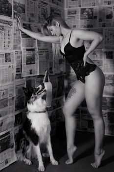 Woman in lingerie poses with dog in black and white artistic setup.