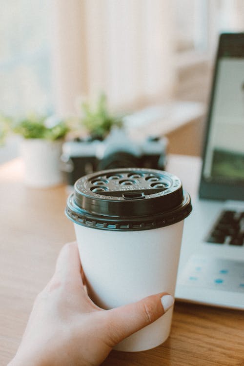 Close-up Of A Person Holding A White Take-out Coffee Cup