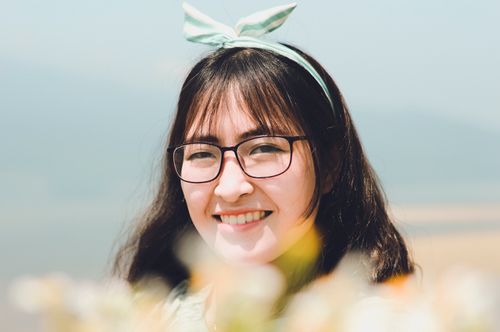 Free Cheerful woman wearing glasses and headband smiling on a sunny day outdoors. Stock Photo