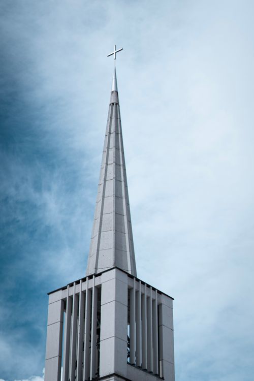 Free A contemporary church steeple with a cross reaching into a dramatic cloudy sky. Stock Photo