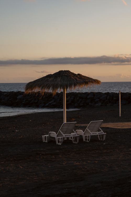 Free Peaceful beach with empty loungers at sunset, ideal for relaxation or vacation themes. Stock Photo