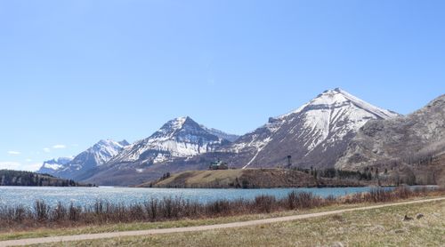 Free Snowy mountains overlooking a serene alpine lake under a clear blue sky. Stock Photo