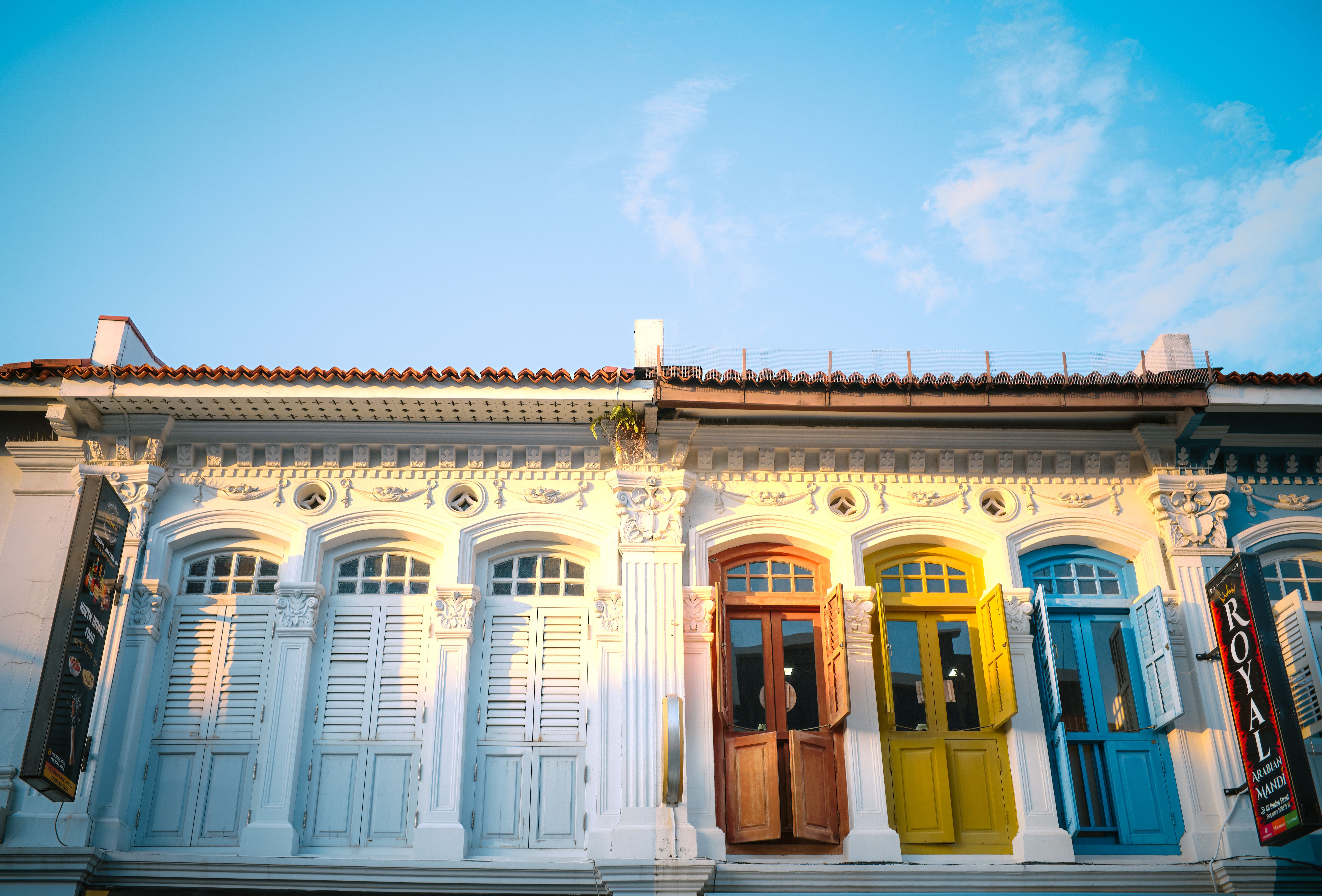 A row of colourful restored shophouses on a sunlit street