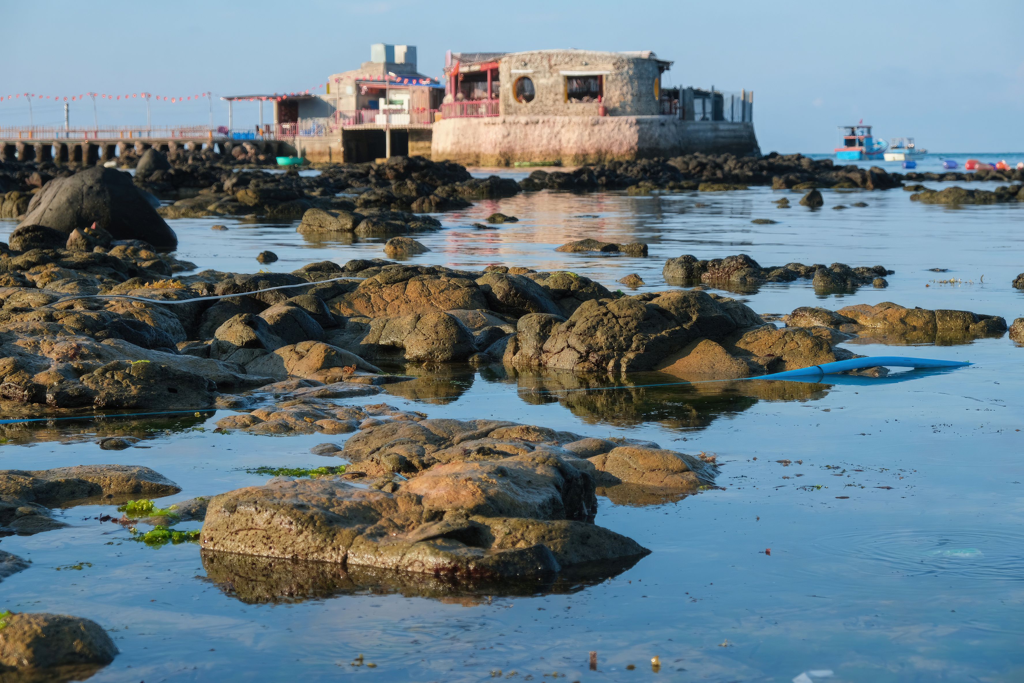 A picturesque rocky shoreline with a historic building and calm waters, ideal for coastal scenes.