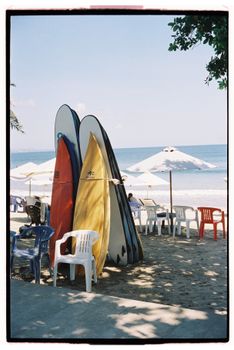 Vibrant surfboards resting on a sandy beach with umbrellas, perfect summer scene.