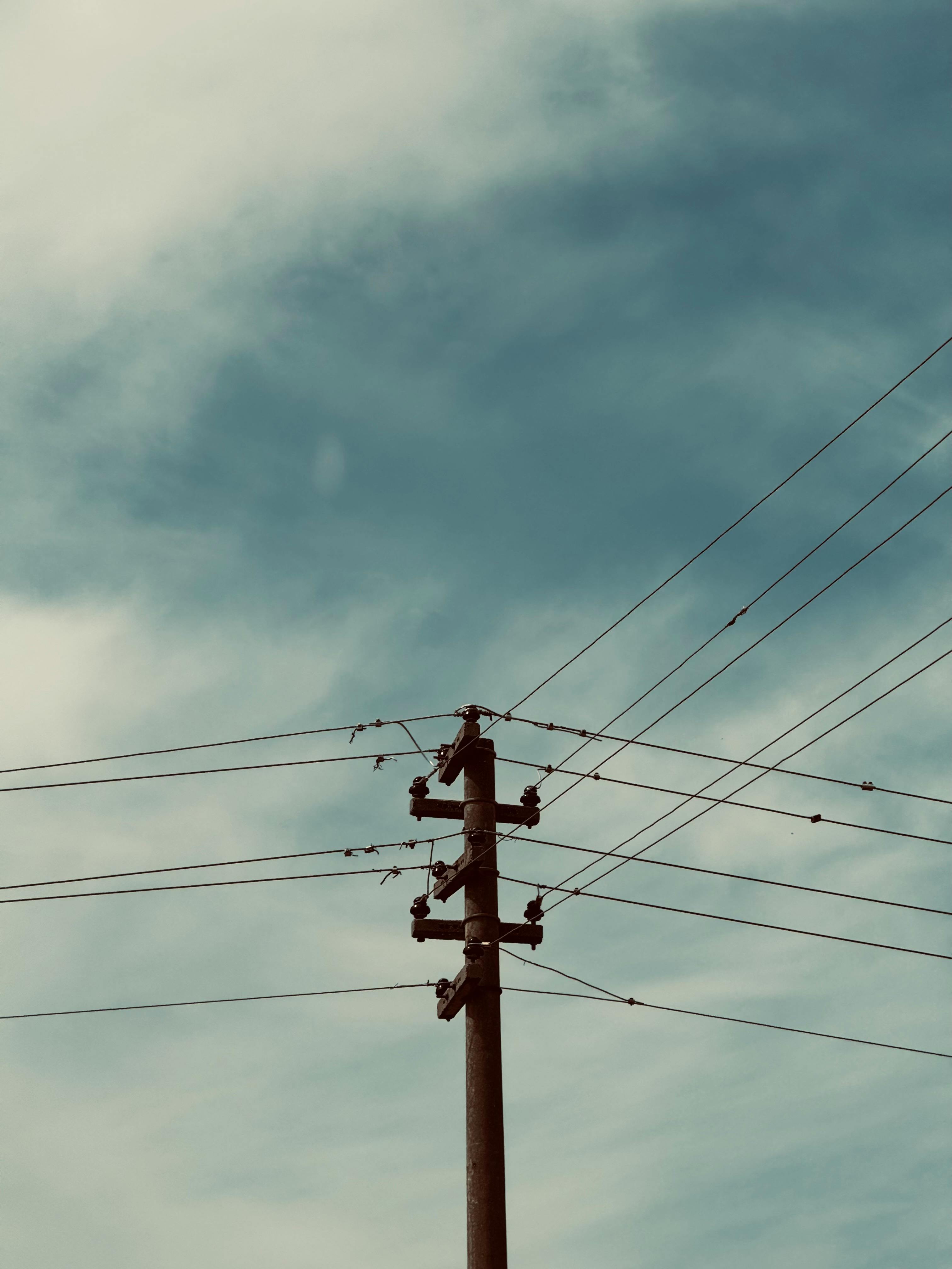 Zadarmo Elektrický stĺp s viacerými drôtmi na pozadí čiastočne zamračenej modrej oblohy s vintage tónom. Fotka z fotobanky