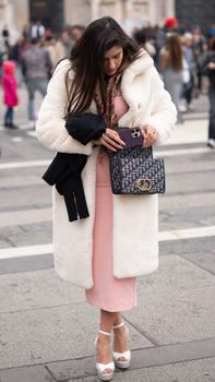 Elegant woman in winter attire with a designer bag in Milan, Italy.