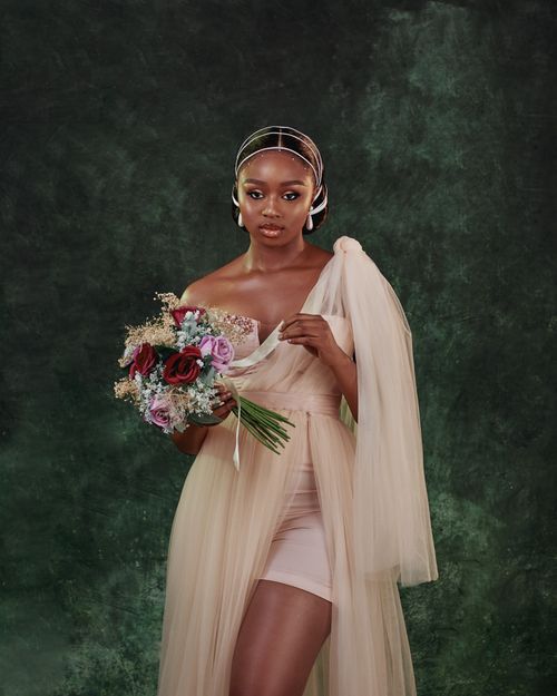 Free Young woman in bridal attire holding a floral bouquet against a textured background. Stock Photo