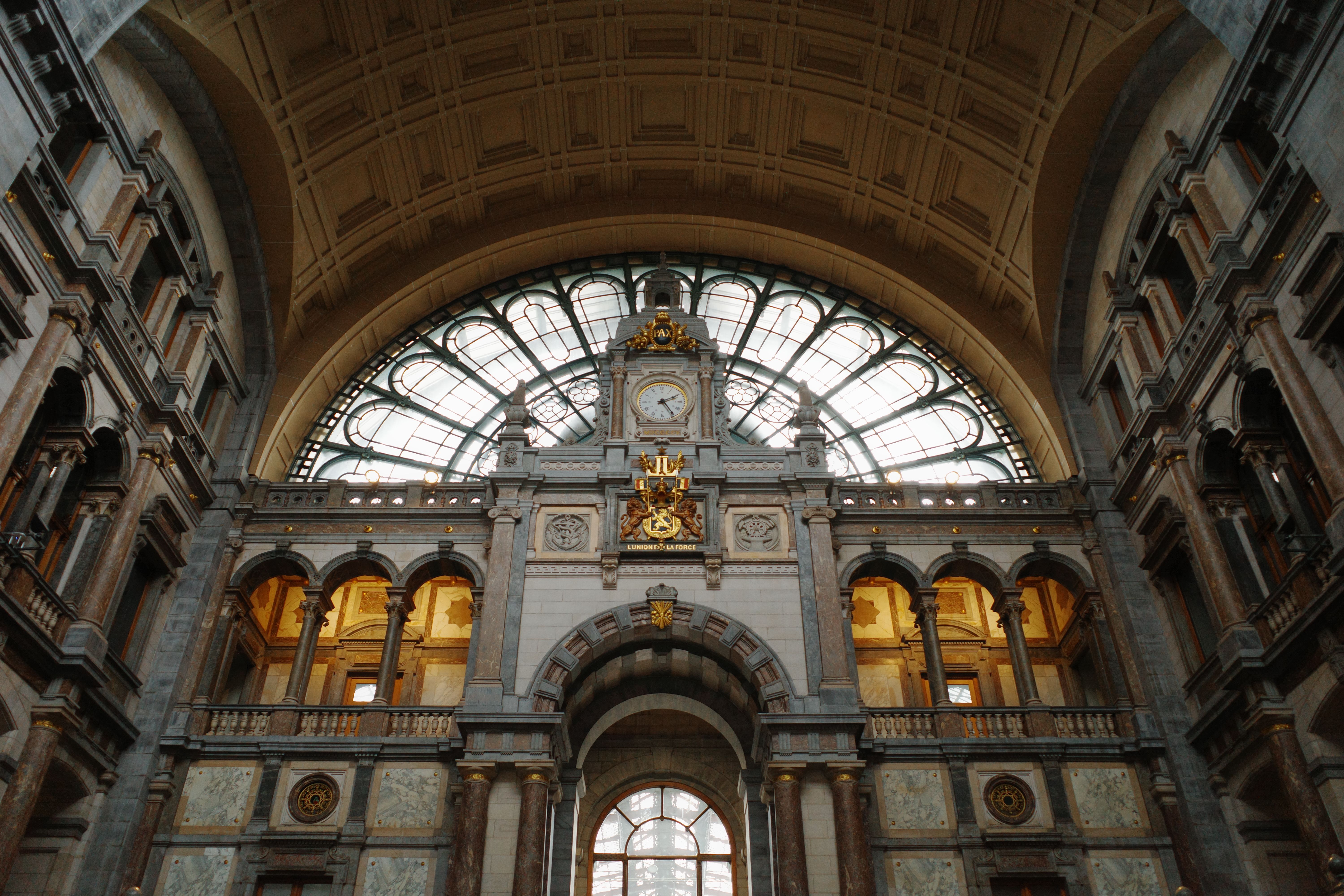 Grand hall of Antwerp Central Station with a vaulted ceiling, large arched window and central clock