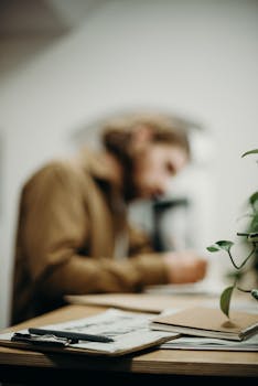 Blurry focus on man working at desk, creating a modern and artistic office atmosphere.