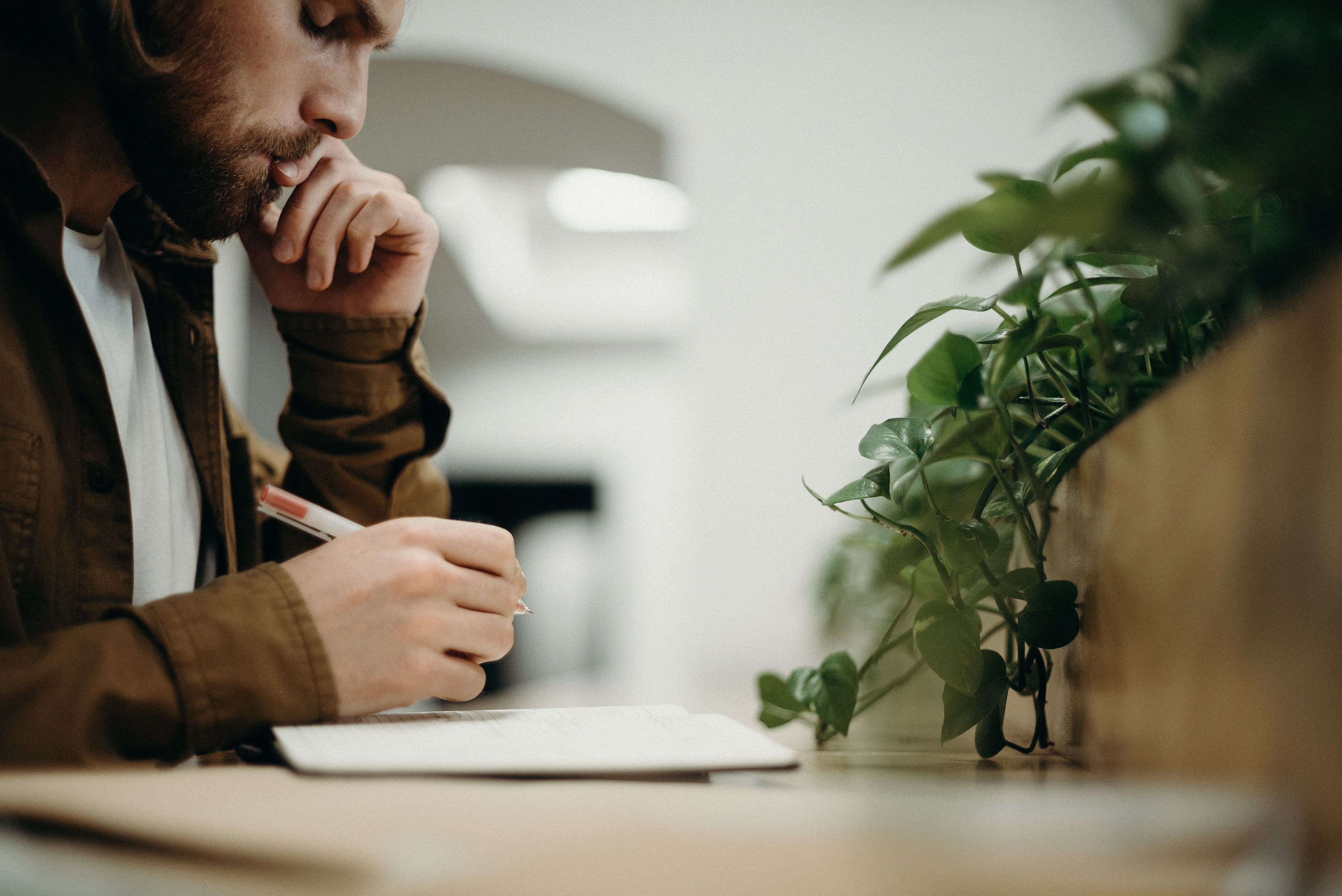 Man Wearing Brown Jacket Using Pen · Free Stock Photo